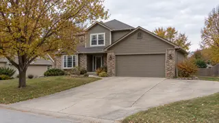 Concrete driveway with light wear and a widened parking area at a suburban home in autumn.