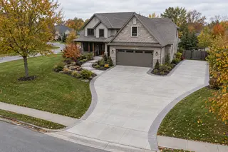 Curved widened concrete driveway with a parking bay and connected front walkway.