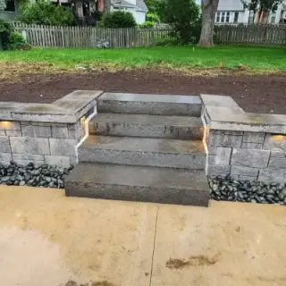 Stone retaining wall with illuminated concrete stairs