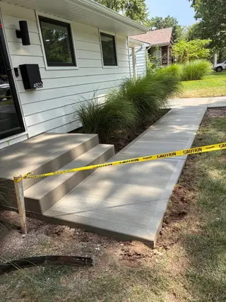 Concrete steps and picture frame sidewalk connecting a front porch to the driveway