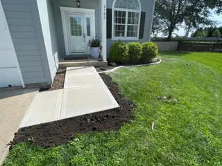 Picture frame concrete sidewalk leading to a front door