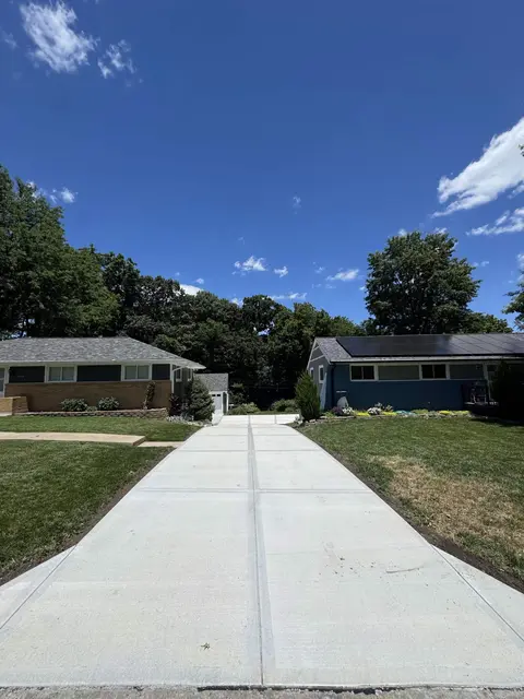 Front yard view of expansive driveway to backyard garage