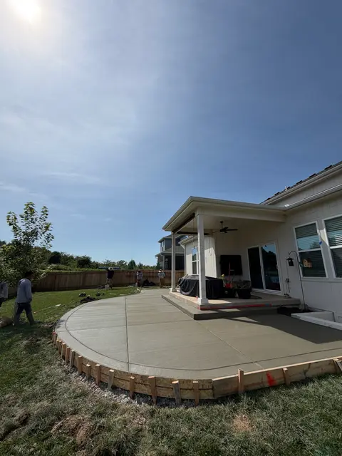 Large rounded concrete patio under a covered porch in Olathe, KS