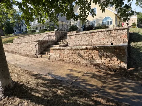 Tiered block retaining wall with concrete steps and iron railing at a Kansas City home