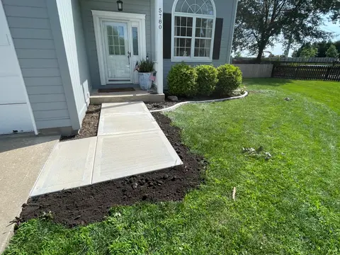 Picture frame concrete sidewalk leading to a front door